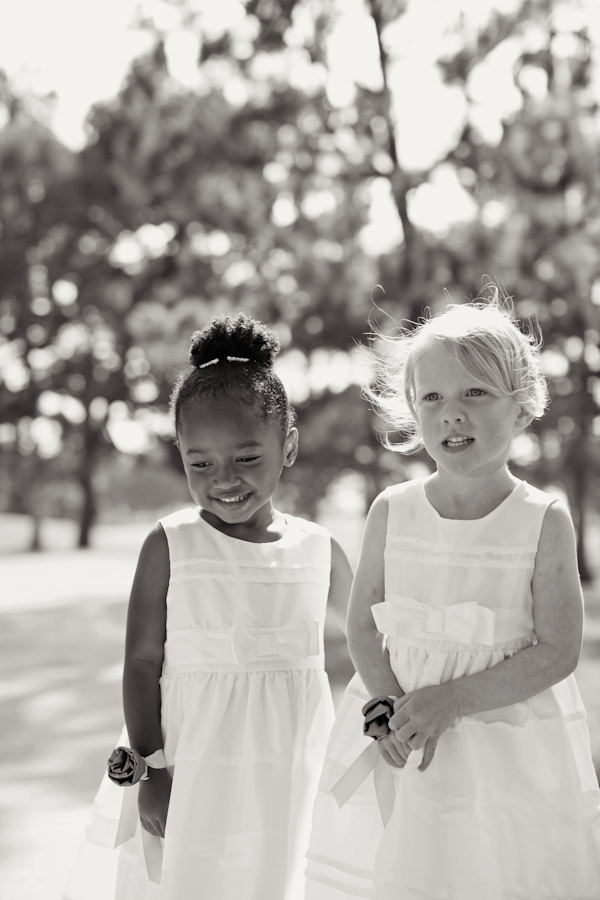 Black and white photo - Adorable flower girls standing together while wearing matching dresses and corsages - photo by San Francisco based wedding photographer Meg Perotti
